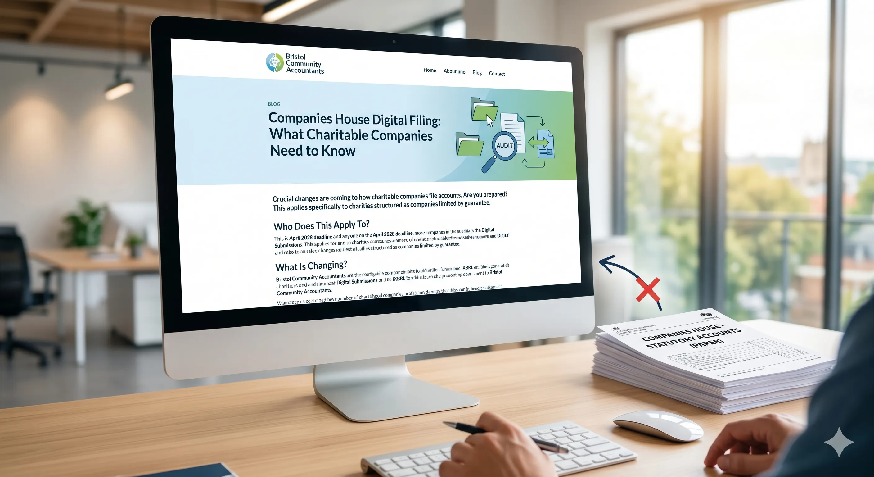 A desk with a computer displaying a blog post about Companies House digital filing next to a tall stack of paper statutory accounts marked with an "X".